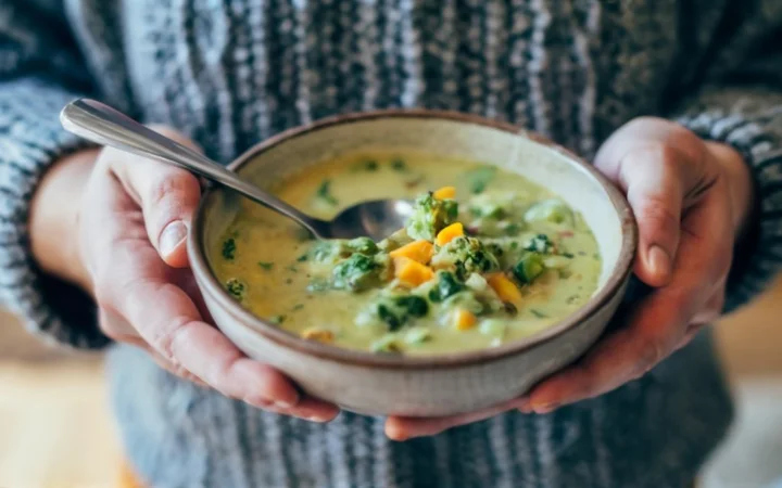 A thoughtful person analyzing a bowl of soup, symbolizing the consideration of its health aspects.