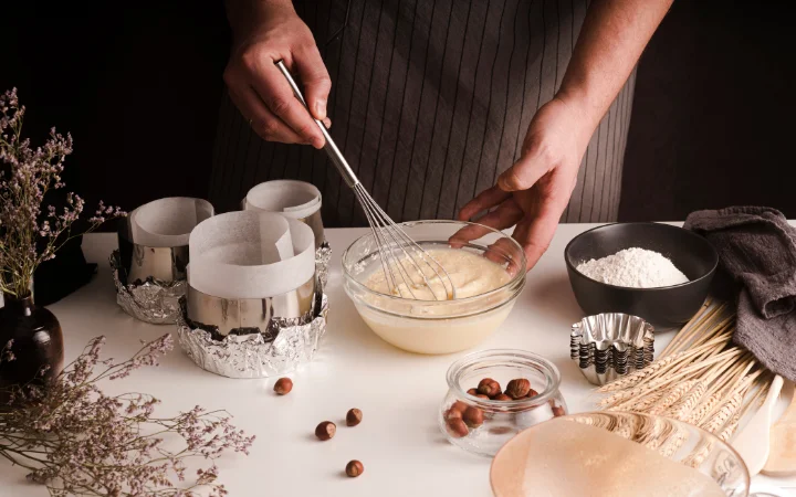 Ingredients for Chocolate Ganache Cake including all-purpose flour, cocoa powder, baking powder, baking soda, sour cream, and eggs, artistically arranged on a kitchen counter.