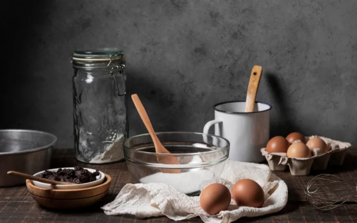 Ingredients like flour, sugar, eggs, butter, cinnamon, and nutmeg artistically arranged on a rustic kitchen counter.