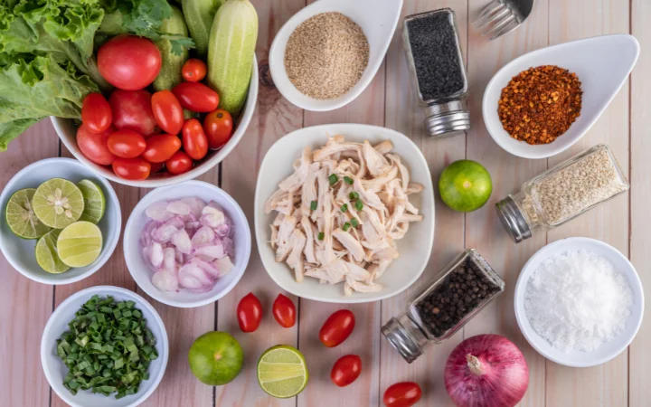 A kitchen countertop spread with the key ingredients for Chicken Gnocchi Soup, including chicken breast, gnocchi, vegetables, and spices, with small tags indicating possible substitutions for each ingredient.