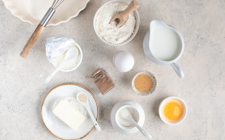  Ingredients  (flour, sugar, butter) laid out on a kitchen counter with a mixing bowl and whisk.