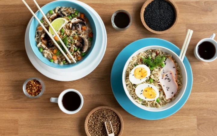 Two bowls of ramen with two mugs of coffee