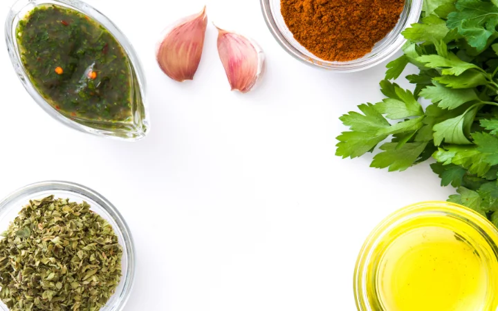 Fresh ingredients for chimichurri sauce (parsley, garlic, olive oil, vinegar) alongside fresh salmon fillets ready for preparation.