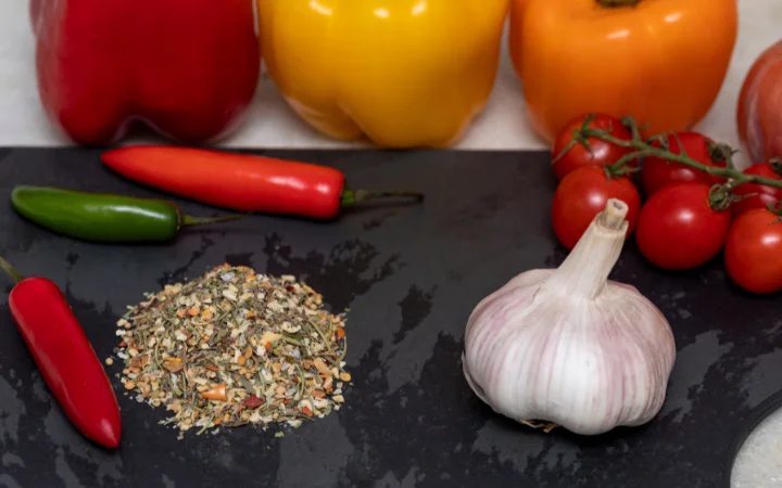 Close-up of Chimichurri Seasoning's ingredients, highlighting garlic, onion, red bell pepper, and green onion.