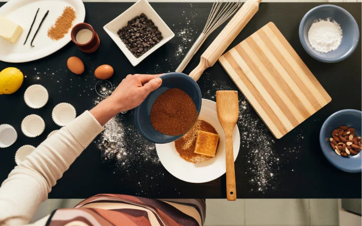 Hands whisking a batter for chocolate coffee cake in a mixing bowl, with baking utensils and ingredients around.