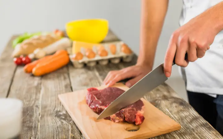 A preparation table where corned beef is being seasoned and vacuum-sealed for sous vide, with spices scattered around and a focus on the sealing process.