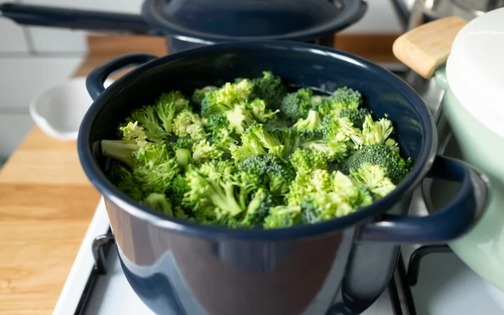  cozy home kitchen, meticulously preparing Broccoli Cheddar Soup. The chef is chopping vegetables, stirring a pot on the stove, and adding ingredients like cheese and cream, illustrating the step-by-step cooking guide for the soup.