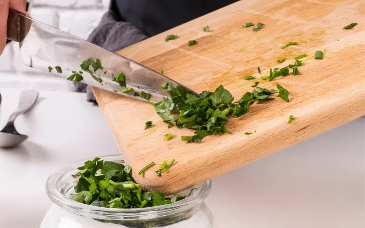 A step-by-step preparation scene of Chimichurri, showing chopped herbs, minced garlic, and the final sauce being whisked together, alongside dishes it complements like grilled steak and vegetables.