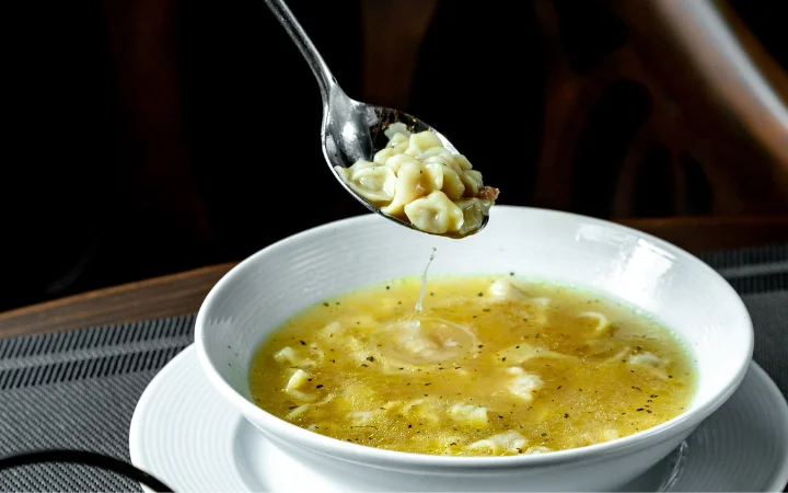 A creative display of different soup variations featuring gnocchi, each representing a unique recipe adaptation – from clear broths to creamy soups. The image should capture the diversity and adaptability of gnocchi in various soup types.