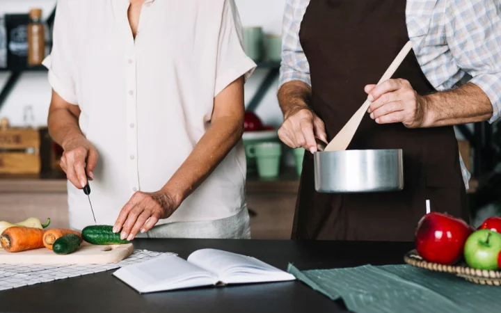 Hands chopping fresh vegetables on a cutting board, with a step-by-step visual guide for making vegetable soup in the background.