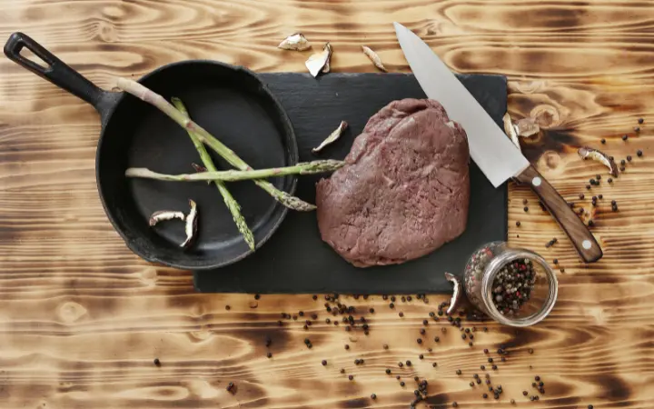 A comparative kitchen setup showing corned beef being cooked using different methods: sous vide, boiling, and roasting, each with distinct cooking equipment and the corned beef in various stages of preparation.