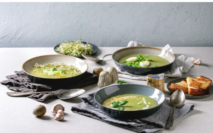 A creative display of various healthier versions of Broccoli Cheddar Soup, including bowls with low-fat, gluten-free, and vegan options. Ingredients like almond milk, vegan cheese, and gluten-free flour are shown, representing dietary adjustments for health and lifestyle.