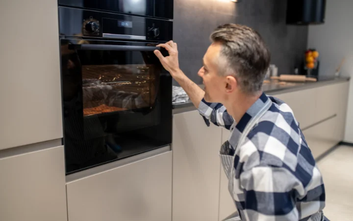 An oven with a built-in thermometer, showing a precise temperature setting, with cookie trays visible through the oven window.