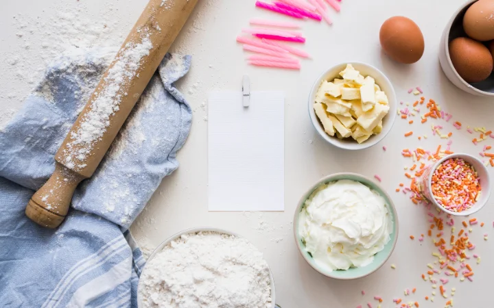  An open cookbook with a page on baking FAQs, surrounded by baking utensils and ingredients.