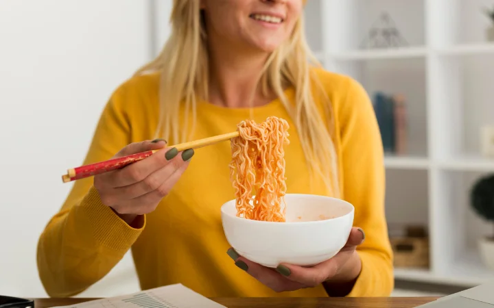 Close-up adult woman eating noodles