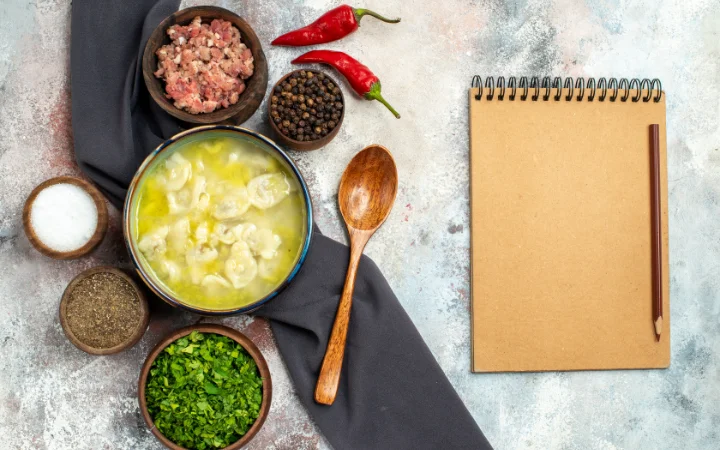 A cozy kitchen setting with a chef answering cooking questions surrounded by notes and recipe books. A pot of chicken gnocchi soup is on the stove, symbolizing the process of addressing common queries and providing expert cooking tips.