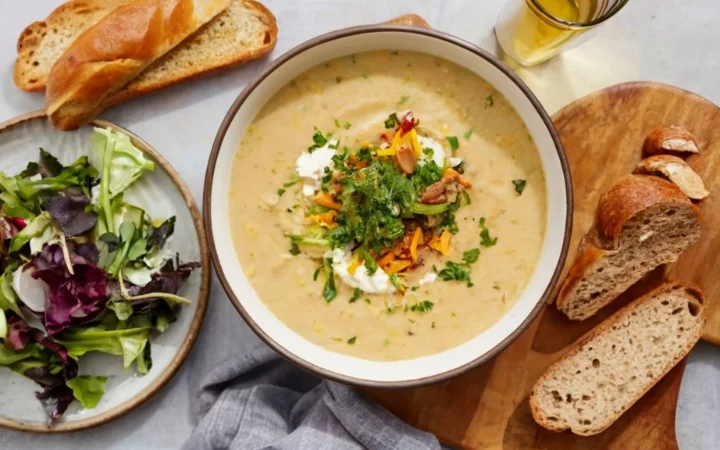 A cozy dining table setting with a hearty bowl of rich panera broccoli cheddar soup, warm bread, and a comforting, homey atmosphere.