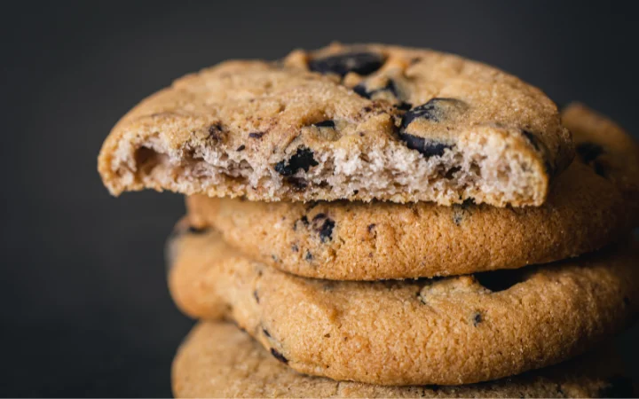 A close-up of a Cowboy Cookie, cut in half to reveal the mix of oats, pecans, and chocolate chips inside, emphasizing the texture and richness of the ingredients.