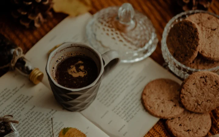 A cozy reading nook with a plate of freshly baked cookies next to a cup of tea and an open family cookbook, symbolizing reflection and tradition.