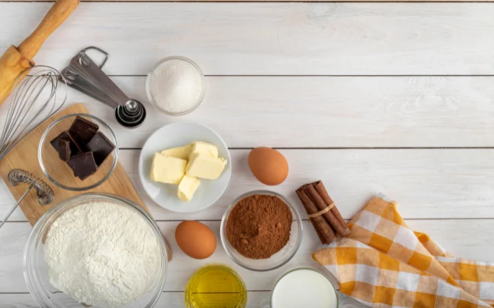 A rustic wooden table displaying key ingredients for grandma's cookies - flour, sugar, butter, and eggs, arranged neatly with a vintage feel.