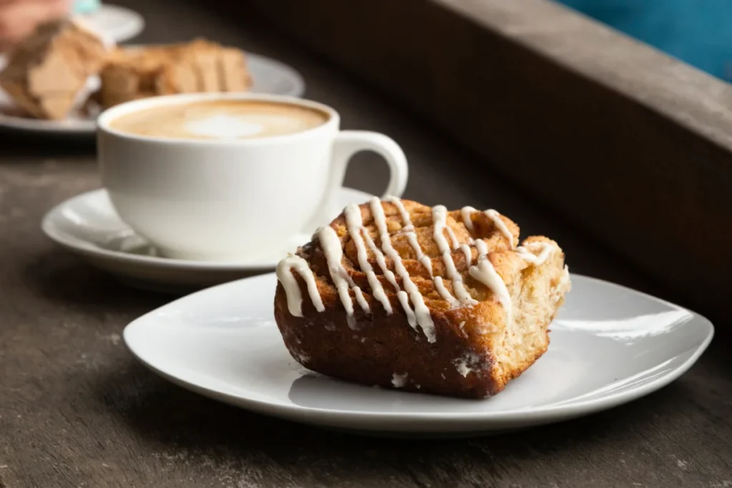 A cozy kitchen scene with a freshly baked coffee cake on a wooden table, steam rising, next to a cup of hot coffee.