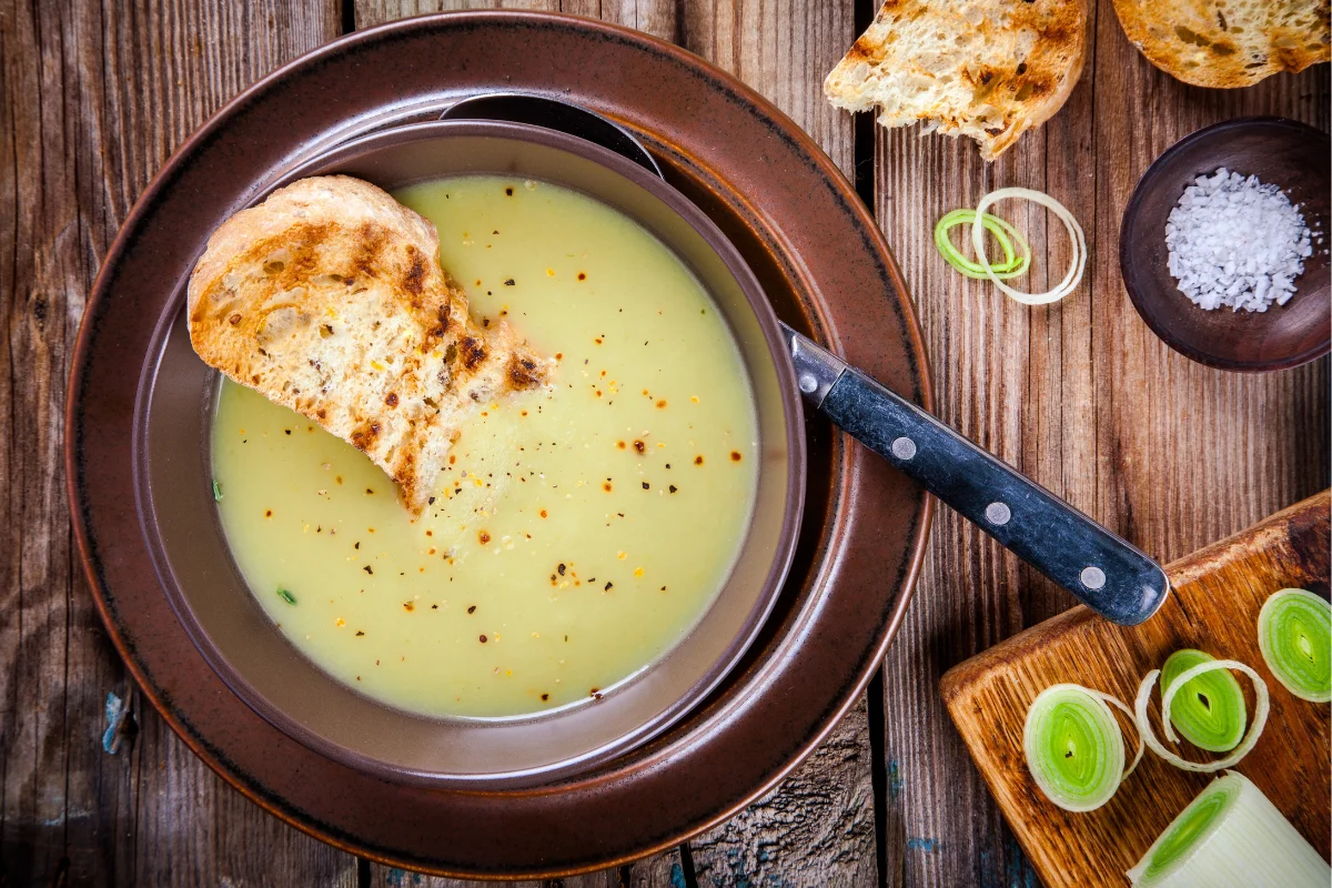 A bowl of Panera's Broccoli Cheddar Soup, steaming and appetizing, placed on a rustic table