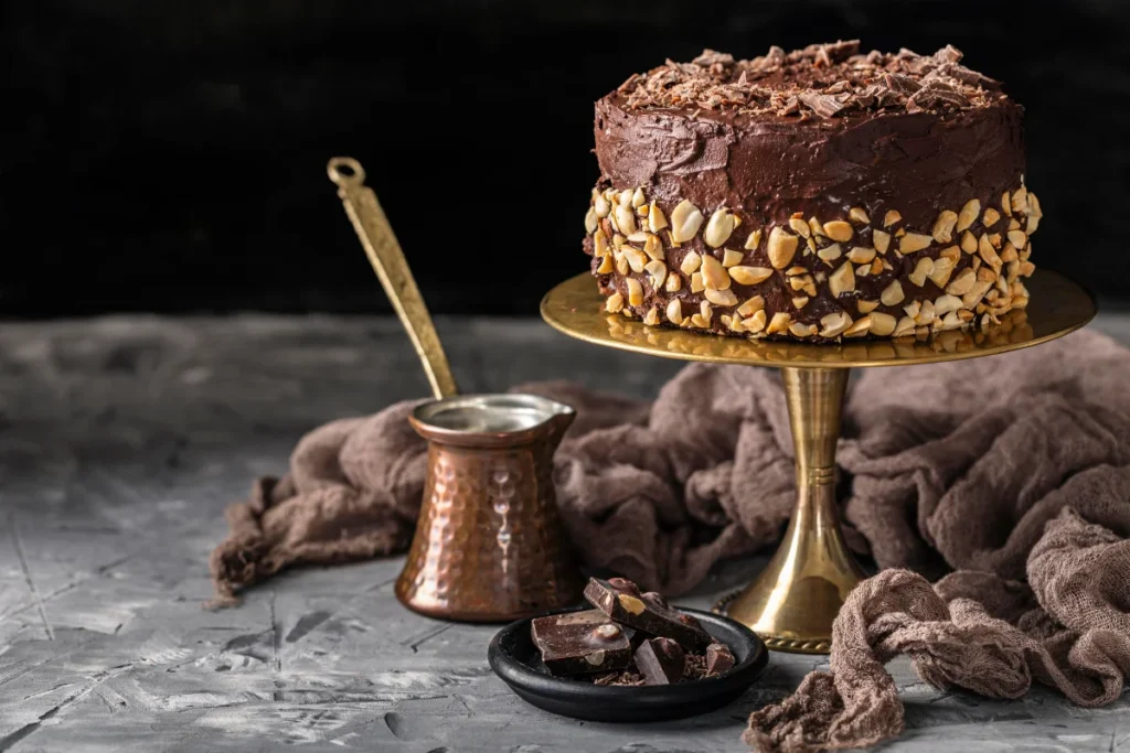 A luxurious Chocolate Ganache Cake with rich chocolate layers and velvety ganache frosting, adorned with chocolate shavings and served on an elegant cake stand.