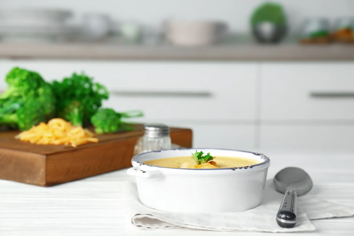 A heartwarming kitchen scene where a pot of Healthy Chicken Gnocchi Soup simmers on the stove. Ingredients like fresh vegetables, herbs, and chicken are displayed around, suggesting a nutritious and comforting cooking process.