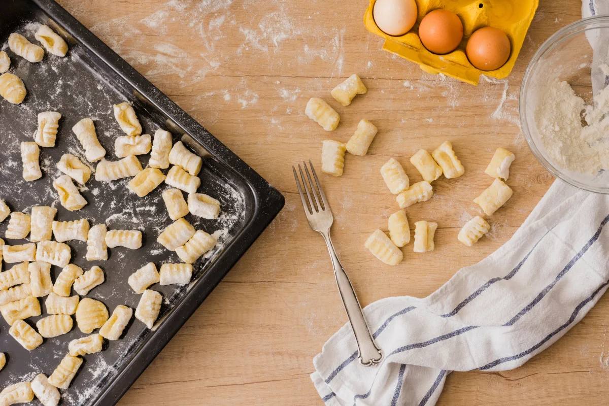 A welcoming kitchen scene featuring a pot of soup with gnocchi, surrounded by ingredients like fresh potatoes, flour, eggs, and herbs. The setup introduces the concept of using gnocchi in soups and highlights its versatility in cooking.