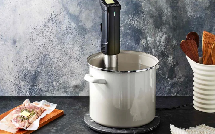 A well-equipped kitchen featuring a high-quality sous vide machine, a large BPA-free plastic container with a lid, and a cast iron skillet, ready for sous vide cooking.