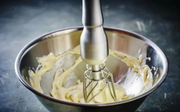 action shot of cream being whipped in stainless steel bowl, capturing motion and transformation