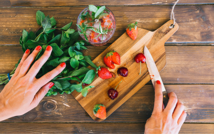 A gourmet kitchen scene with chefs preparing dishes and drinks garnished with fresh herbs, showcasing the herb's culinary versatility.