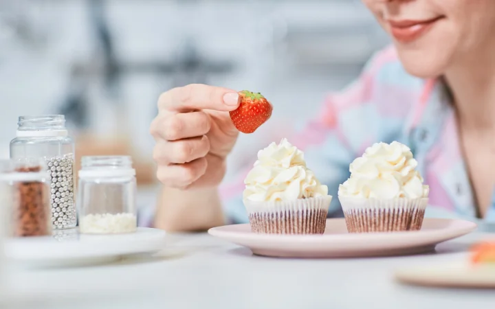 women garniching mufins with strawberry 