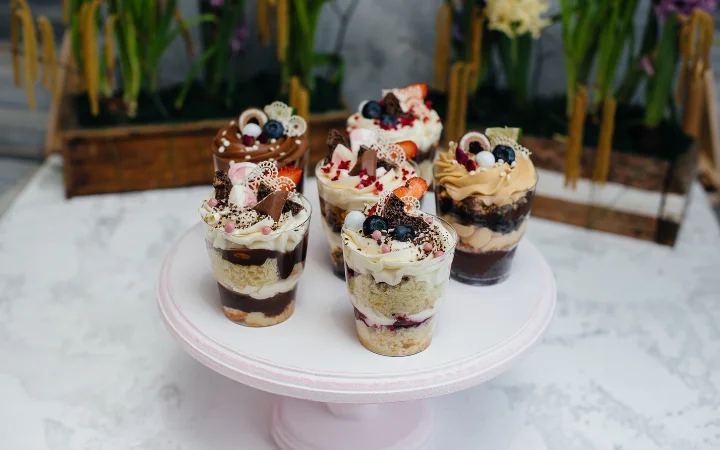 A celebratory scene of a home baker presenting a tray of desserts adorned with homemade flavored whipped cream to a group of friends gathered around a kitchen island, sharing smiles and toasts.