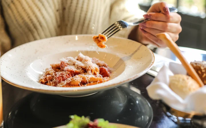 Man are eating pasta with tomato sauce parmesan vegetables meat side view